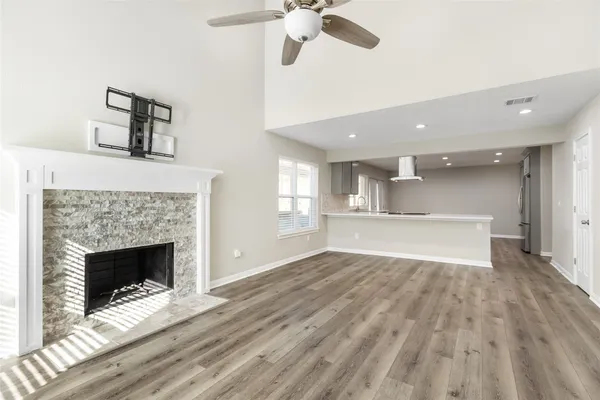 a view of an empty room with wooden floor fireplace and a window