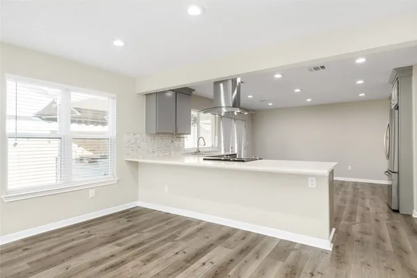 a view of an empty room with wooden floor fireplace and a window