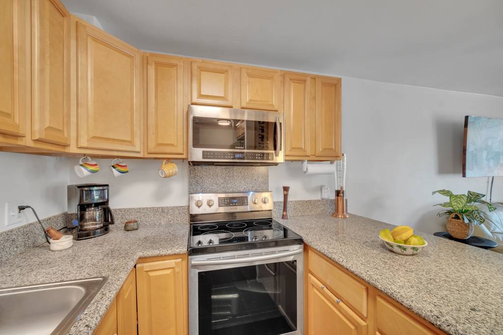 4156 Rice Street, Unit 107 Lihue, HI 96766 - Photo 7 of 29 a kitchen with stainless steel appliances granite countertop a sink a stove and a microwave