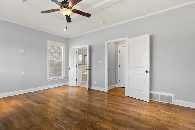 a view of an empty room with window and wooden floor