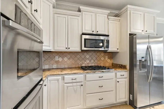 a kitchen with white cabinets and stainless steel appliances