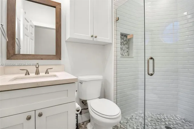 a bathroom with a granite countertop toilet sink and mirror