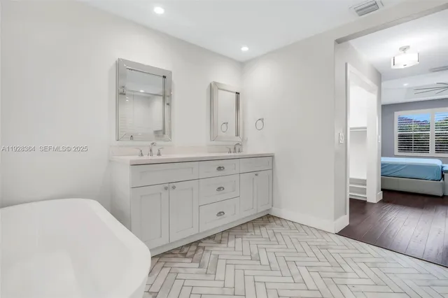 a spacious bathroom with a double vanity sink a mirror and a bathtub