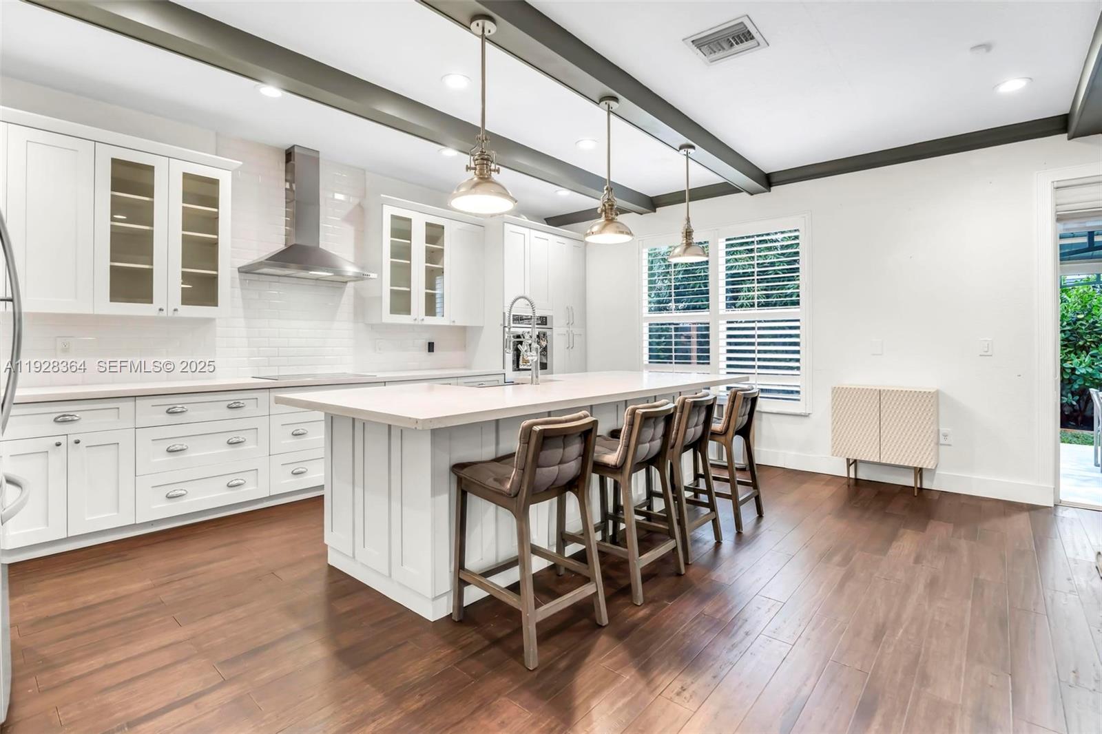 16437 Southwest 28th Street Miramar, FL 33027 - Photo 4 of 34 a kitchen with stainless steel appliances granite countertop a table chairs stove and wooden floor