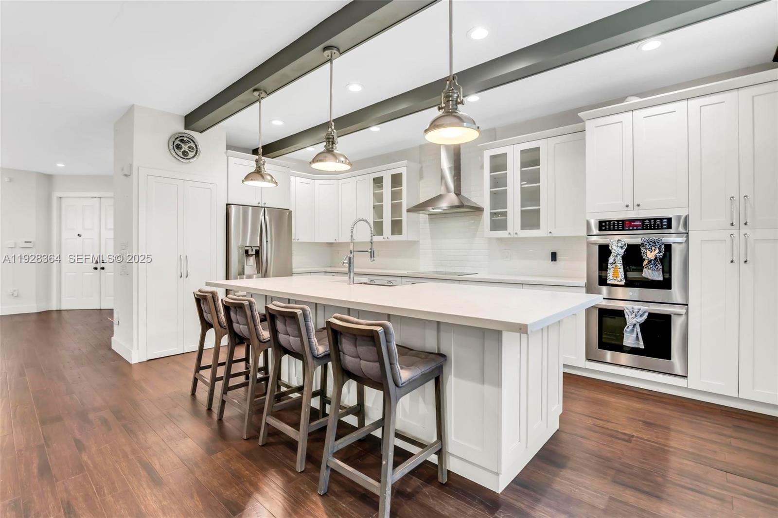 16437 Southwest 28th Street Miramar, FL 33027 - Photo 5 of 34 a kitchen with stainless steel appliances kitchen island a table chairs in it and wooden floors