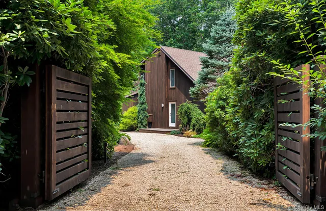 a pathway of a house with wooden fence next to a road