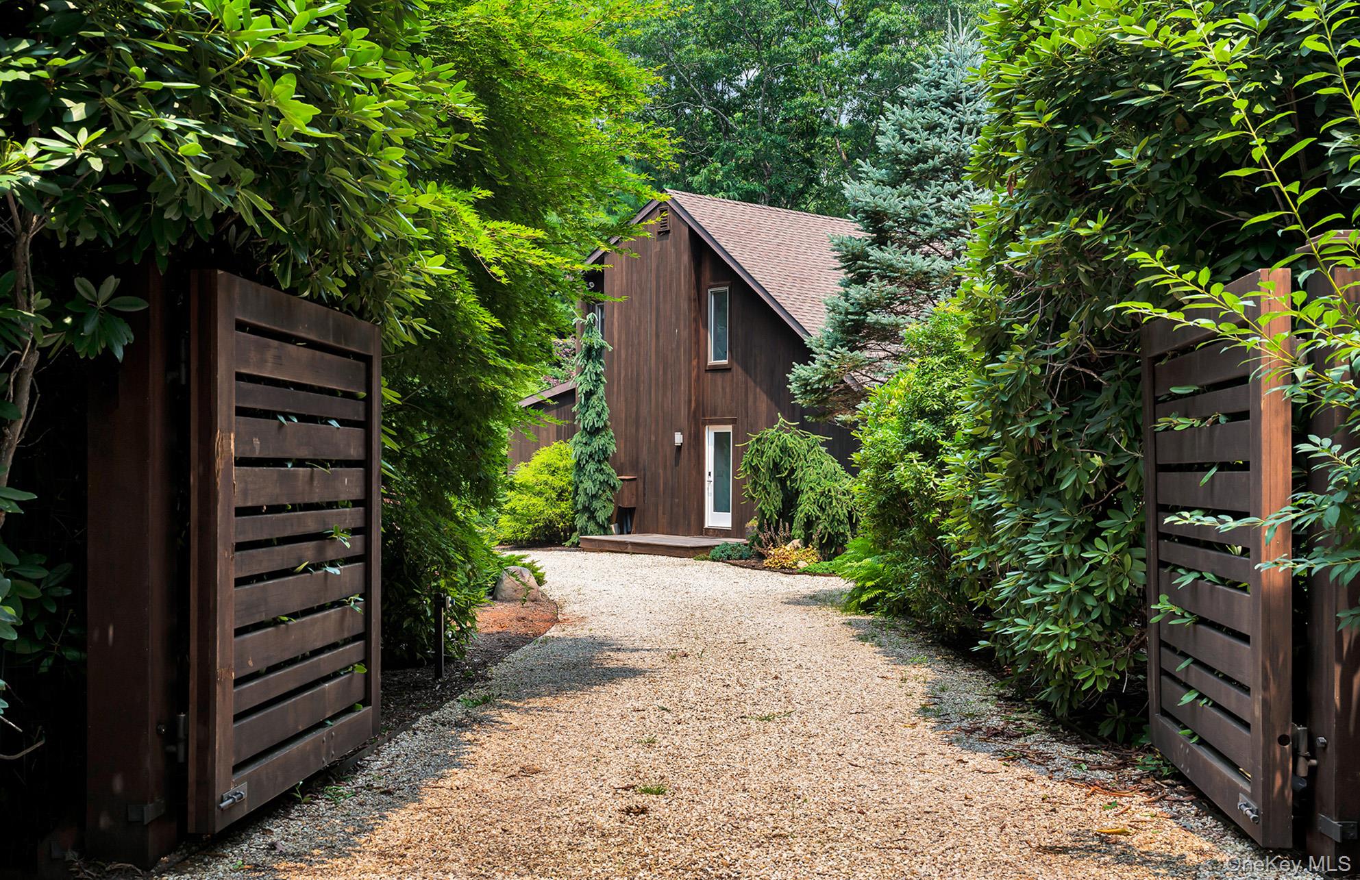 a pathway of a house with wooden fence next to a road