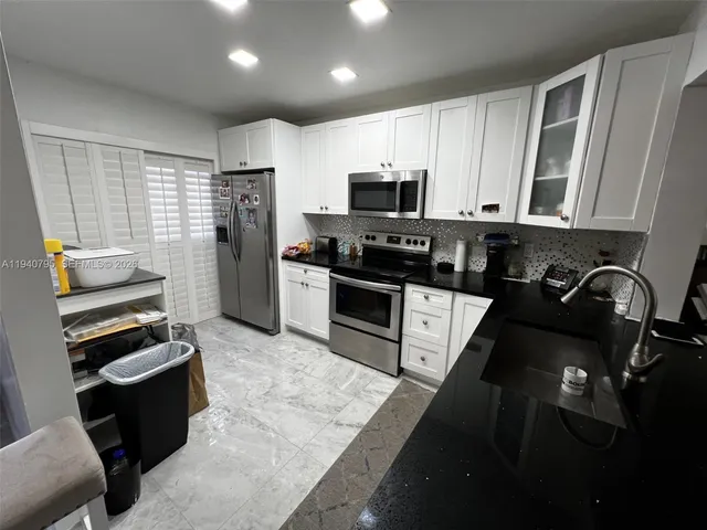 a kitchen with stainless steel appliances kitchen island granite countertop a stove a sink dishwasher a refrigerator and a microwave