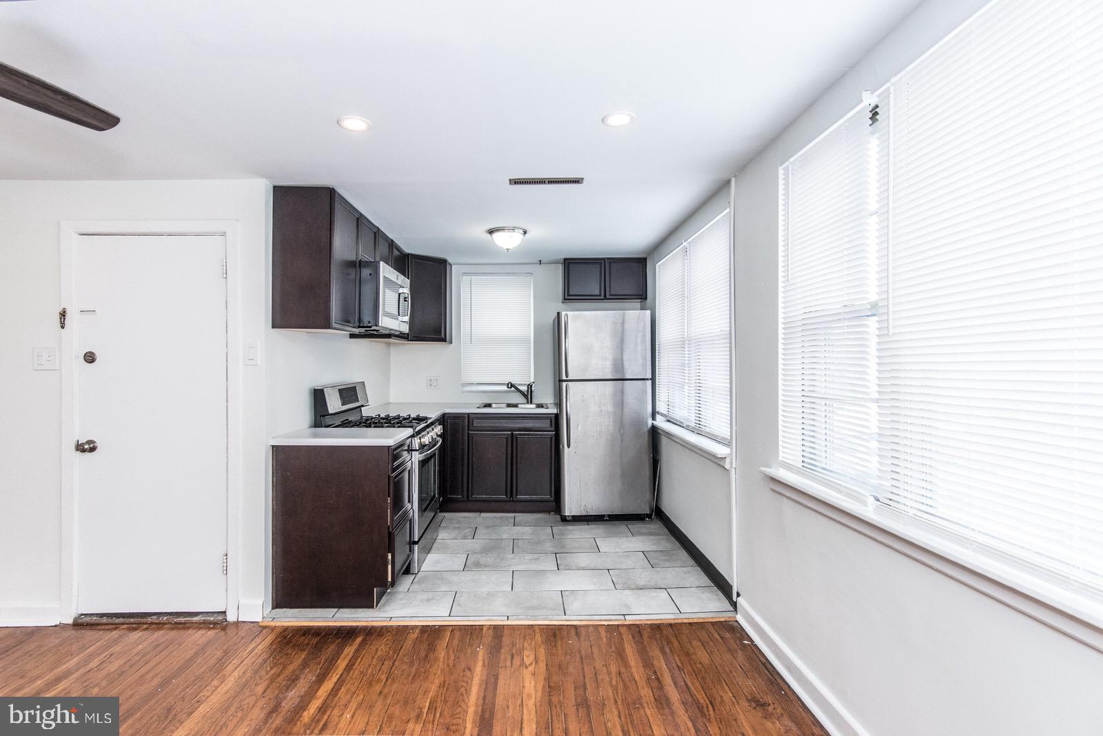 a kitchen with stainless steel appliances granite countertop a refrigerator a sink dishwasher a stove and white countertops with wooden floor