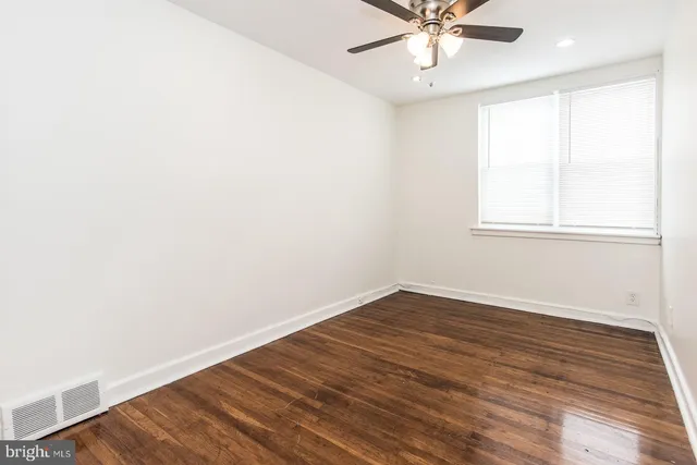 an empty room with wooden floor fan and windows