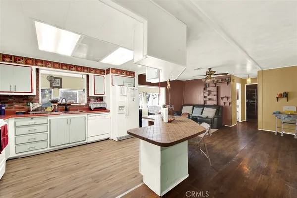 a kitchen with stainless steel appliances kitchen island granite countertop a table chairs in it and wooden floors