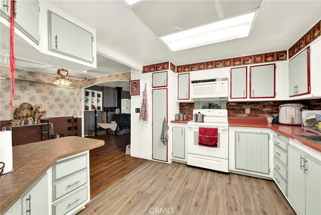 a kitchen with stainless steel appliances granite countertop a refrigerator a stove and white cabinets with wooden floor