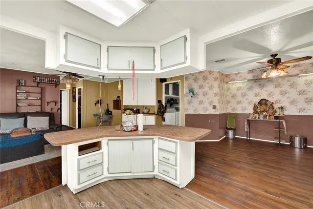 a kitchen with a sink dishwasher a stove and white cabinets with wooden floor