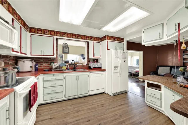 a kitchen with a refrigerator a stove top oven a sink and dishwasher with wooden floor