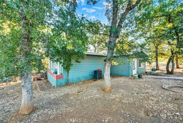 a view of a house with large tree and wooden fence