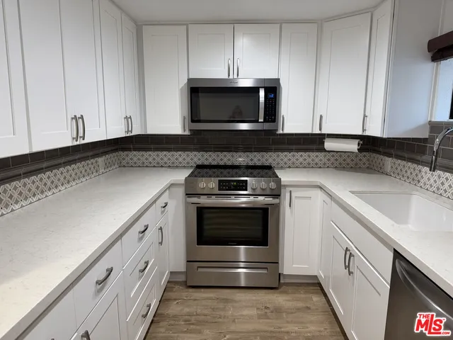 a kitchen with granite countertop white cabinets and stainless steel appliances