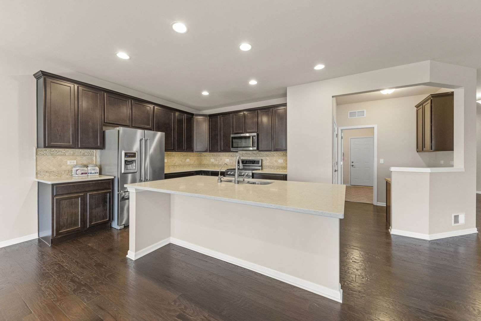 1433 Ruby Drive Yorkville, IL 60560 - Photo 8 of 25 a large white kitchen with stainless steel appliances granite countertop a refrigerator stove a sink and dishwasher with wooden floor
