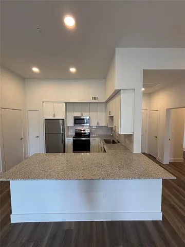 a large kitchen with kitchen island granite countertop a refrigerator a stove and a sink