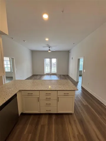 a view of a kitchen with granite countertop white cabinets and wooden floor