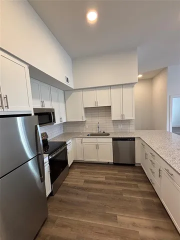 a large kitchen with cabinets wooden floor and stainless steel appliances