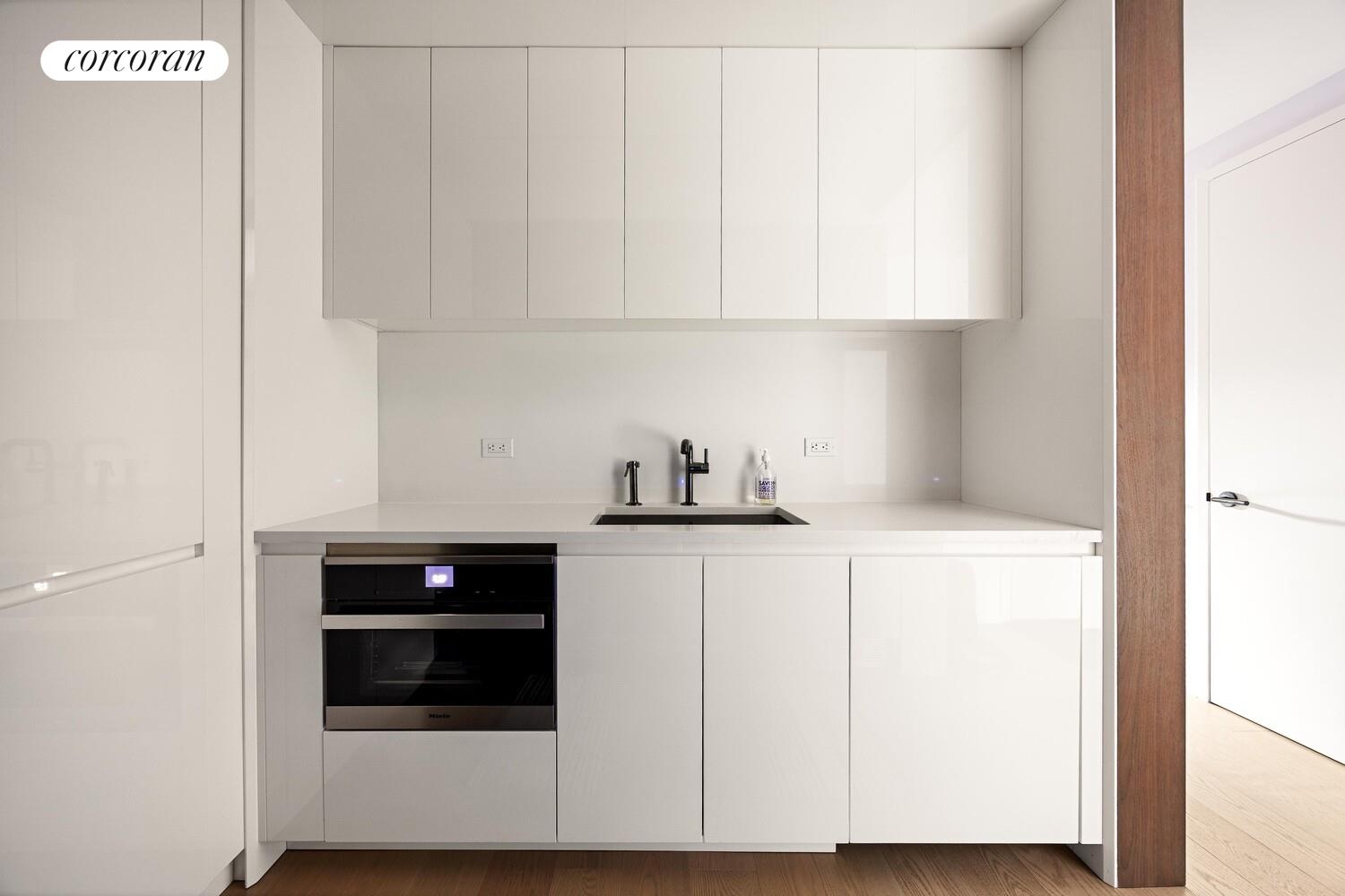 196 Orchard Street, Unit 5K Manhattan, NY 10002 - Photo 5 of 8 a kitchen with white cabinets and white appliances