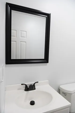 a bathroom with a sink a toilet and mirror