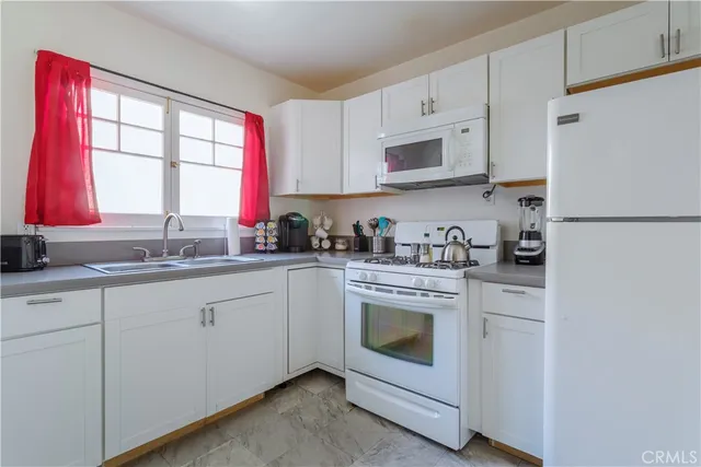 a kitchen with stainless steel appliances granite countertop white cabinets a sink and a window