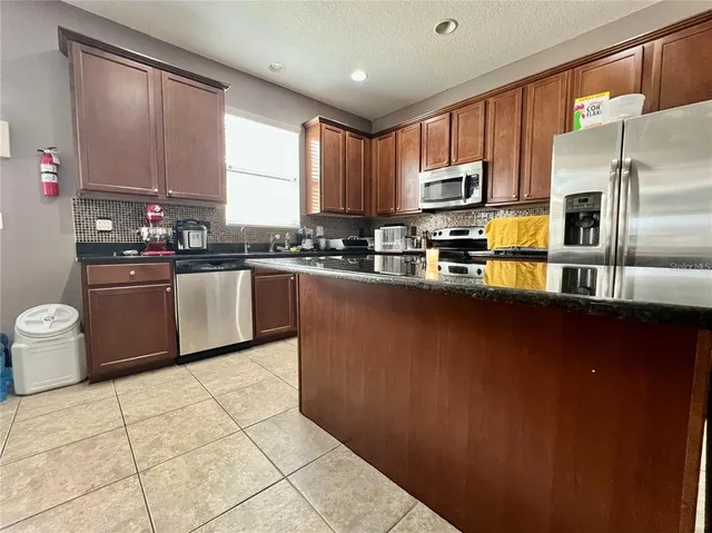 a kitchen with stainless steel appliances granite countertop a sink stove refrigerator and cabinets