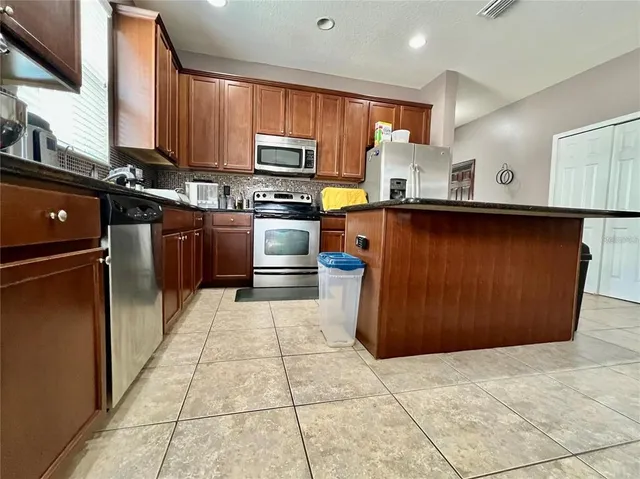 a kitchen with stainless steel appliances a sink a stove top oven a refrigerator and cabinets
