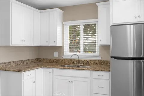 a kitchen with granite countertop white cabinets and a refrigerator