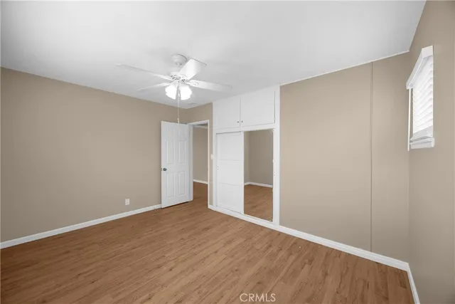 an empty room with wooden floor and a ceiling fan
