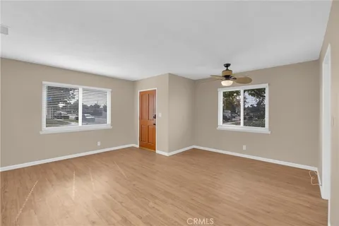 a view of an empty room with window and wooden floor