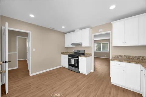 a kitchen with granite countertop a stove top oven and cabinets
