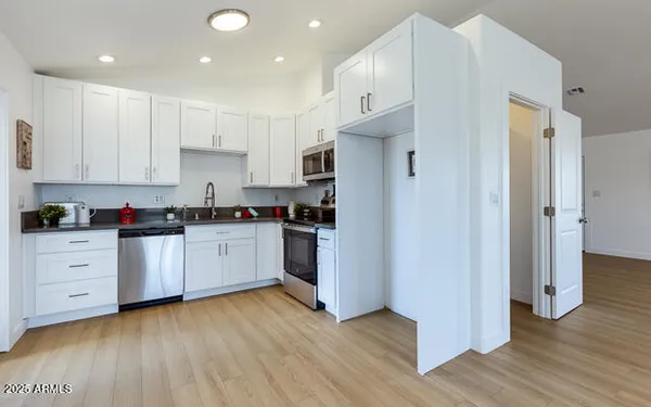 a kitchen with white cabinets and black appliances