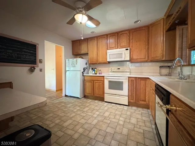 a living room with couches a flat screen tv and a refrigerator
