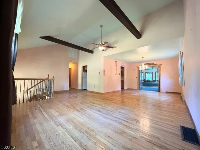 an empty room with wooden floor chandelier and windows