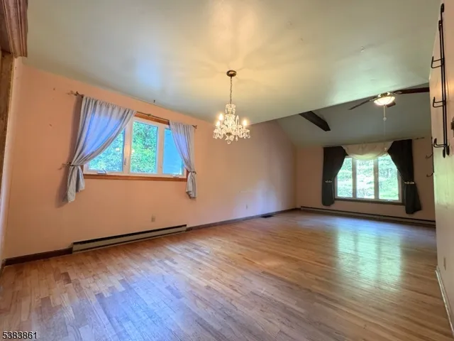 a view of an empty room with window and wooden floor