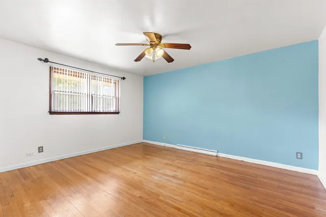 a view of a big room with wooden floor and windows