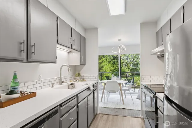 a open kitchen with stainless steel appliances granite countertop a stove a sink dishwasher and cabinets with wooden floor