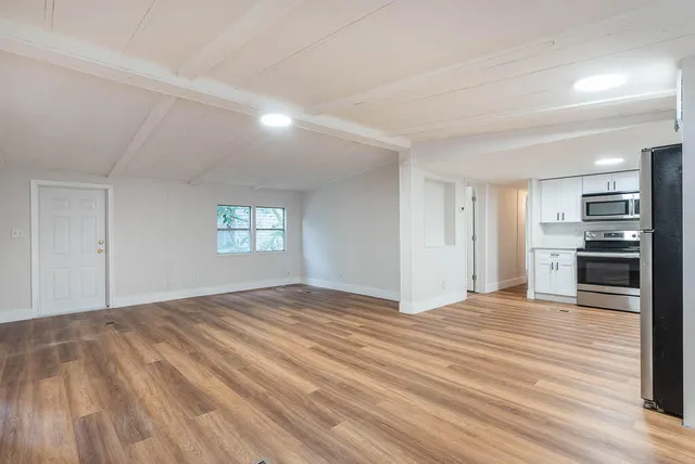a view of empty room with kitchen and a window