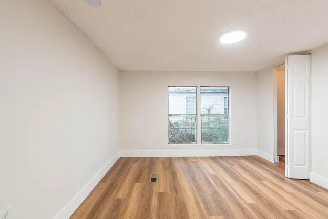 an empty room with wooden floor and windows