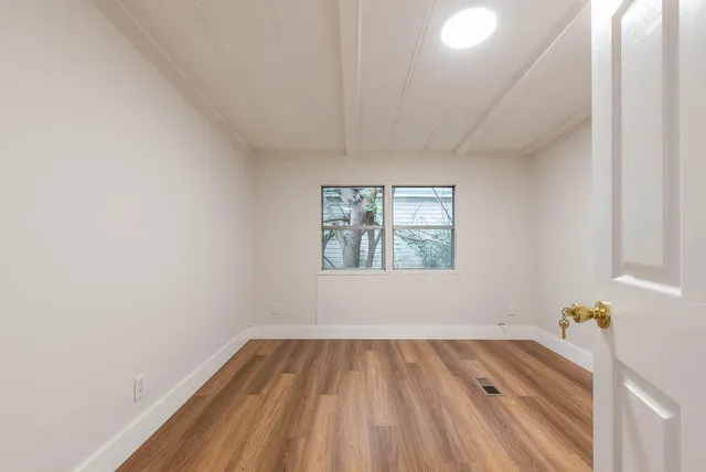 a view of a room that has a window and wooden floor