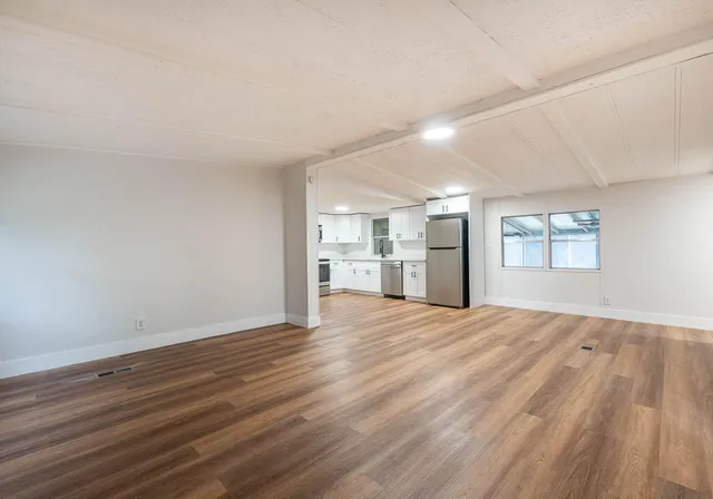 a view of empty room with wooden floor and windows
