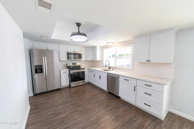 a large kitchen with white cabinets and stainless steel appliances