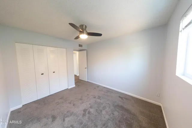 an empty room with a window and a ceiling fan