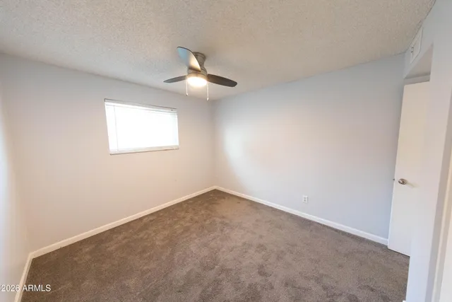 an empty room with a window and ceiling fan