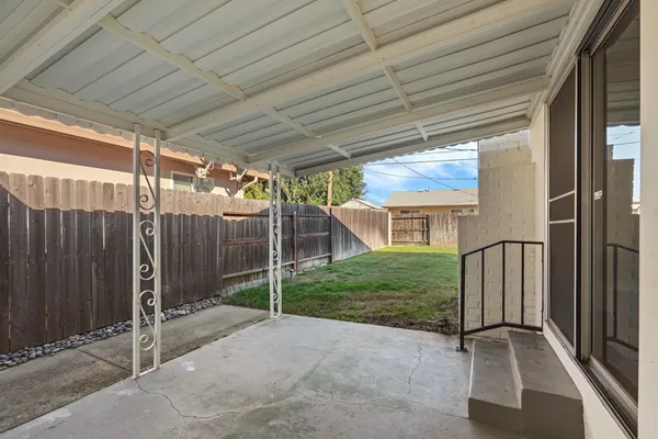 a view of a backyard with wooden fence and large trees