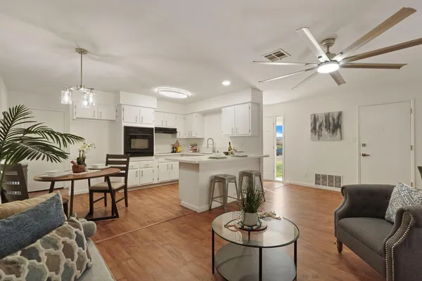 a living room with furniture kitchen view and a chandelier