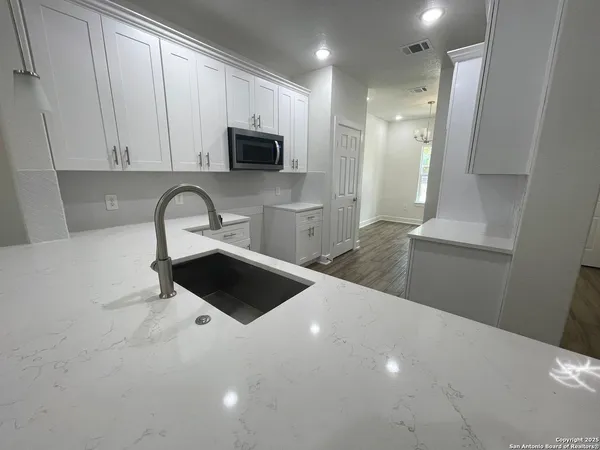 a kitchen with stainless steel appliances a sink a microwave a refrigerator and cabinets