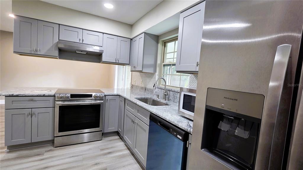 401 Noya Lane Apopka, FL 32712 - Photo 6 of 14 a kitchen with stainless steel appliances granite countertop a stove a sink and a refrigerator